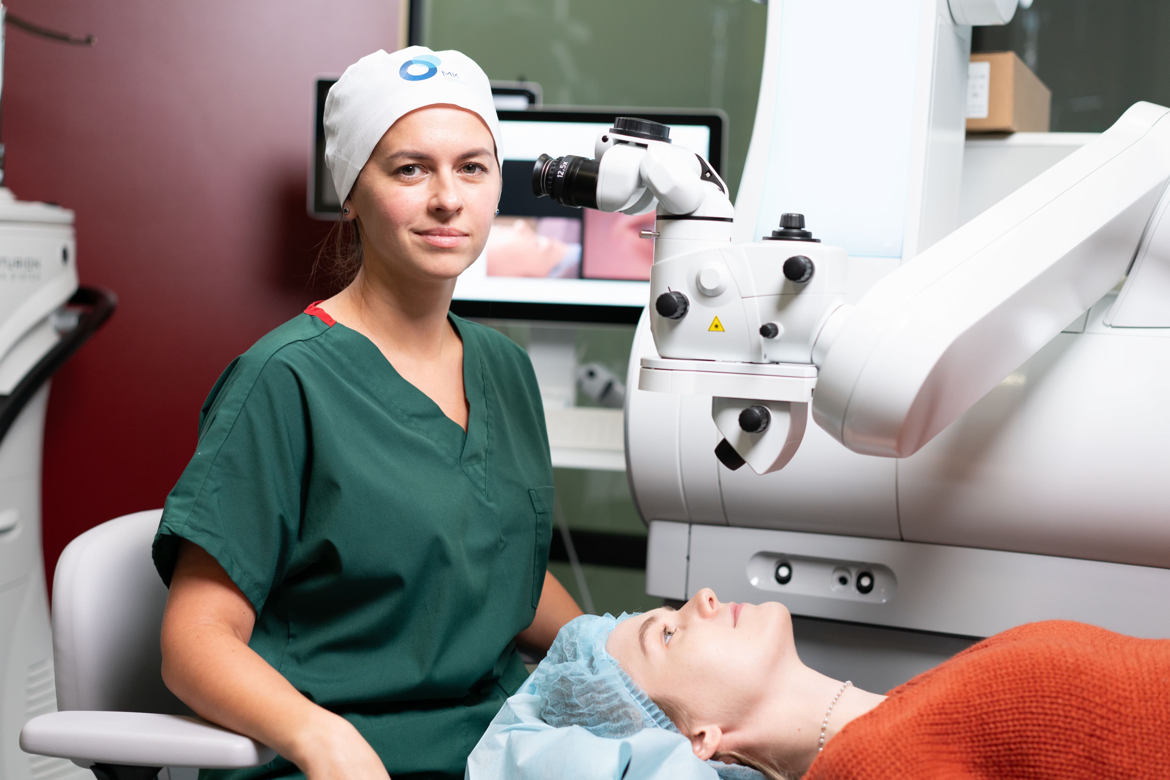 Женщина-офтальмолог рядом с пациенткой перед процедурой лазерной коррекции зрения, высокоточное офтальмологическое оборудование
