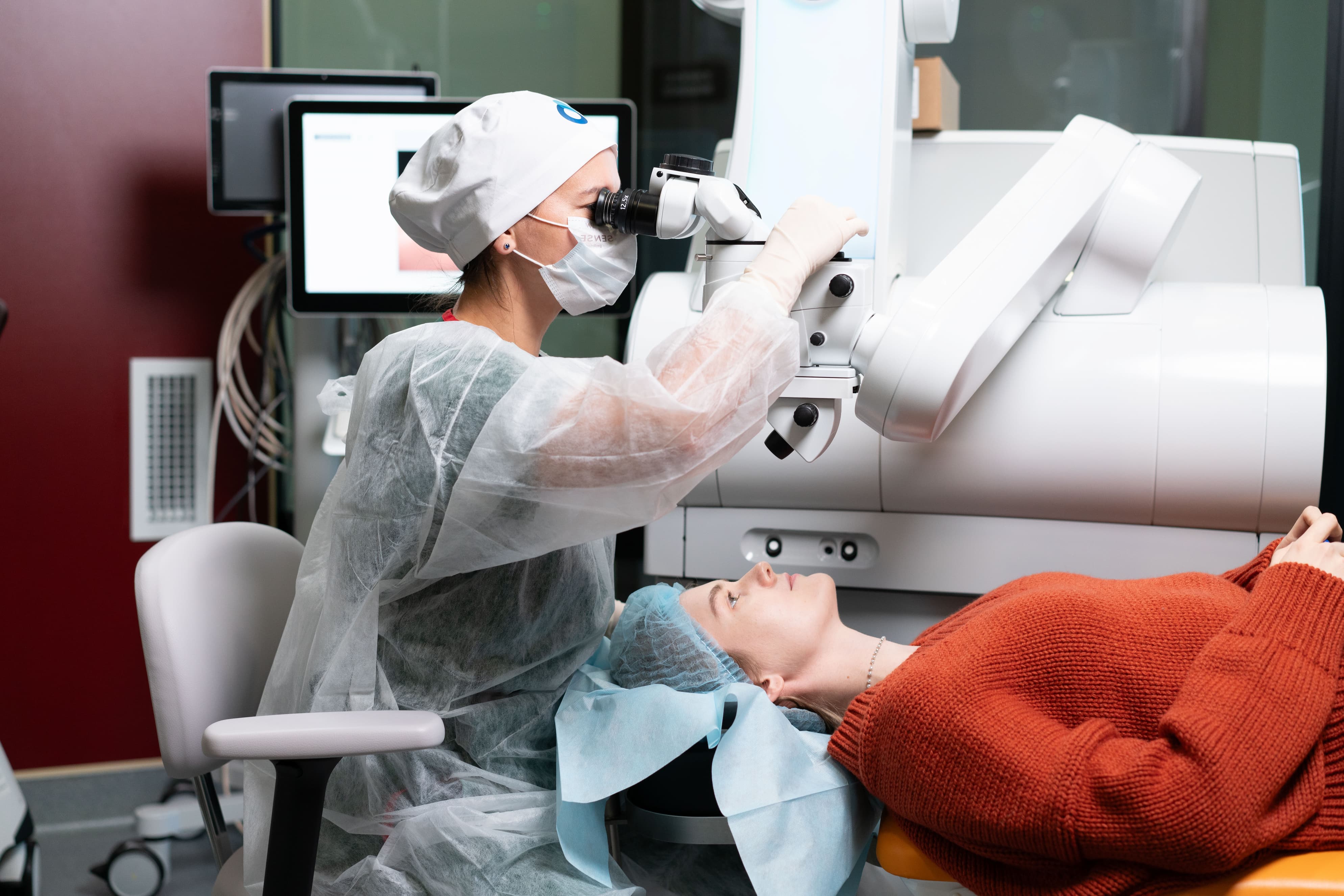 Женщина-офтальмолог рядом с пациенткой перед процедурой лазерной коррекции зрения, высокоточное офтальмологическое оборудование